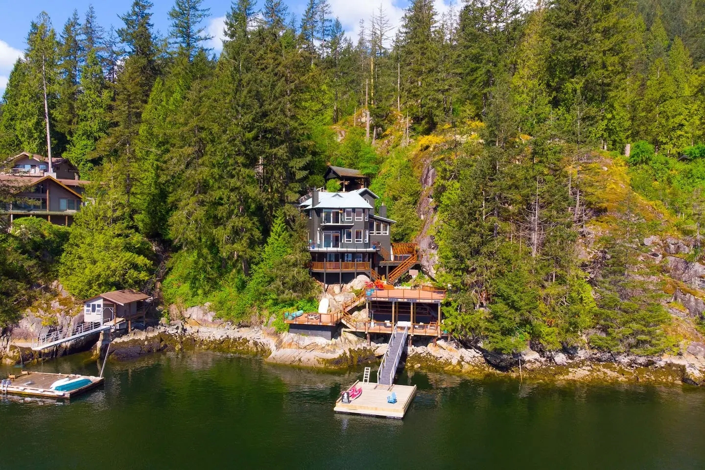 Aerial view of the waterfront home on the forested shore of Indian Arm, with its private dock
