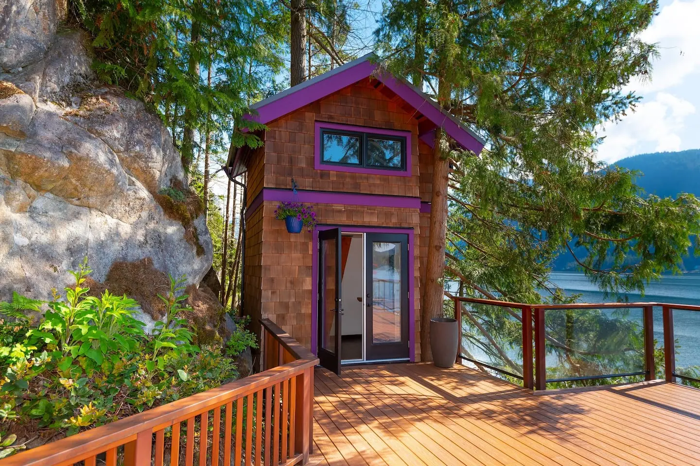 Cedar-shingle cabin with purple trim on the waterfront deck