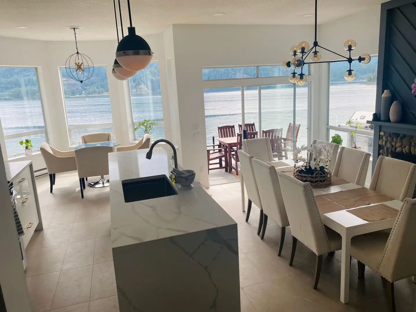 Kitchen island and dining table beside windows on the water