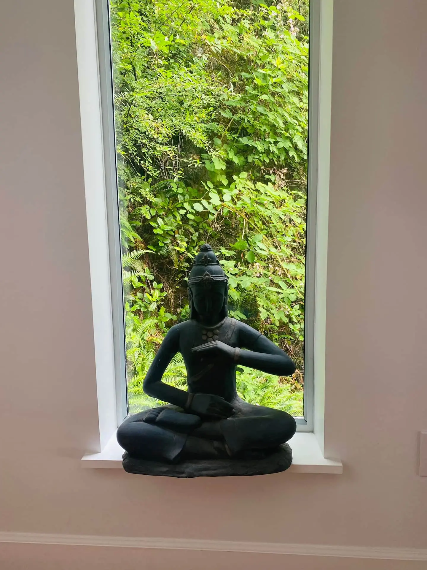 Buddha statue in a tall window framing the forest