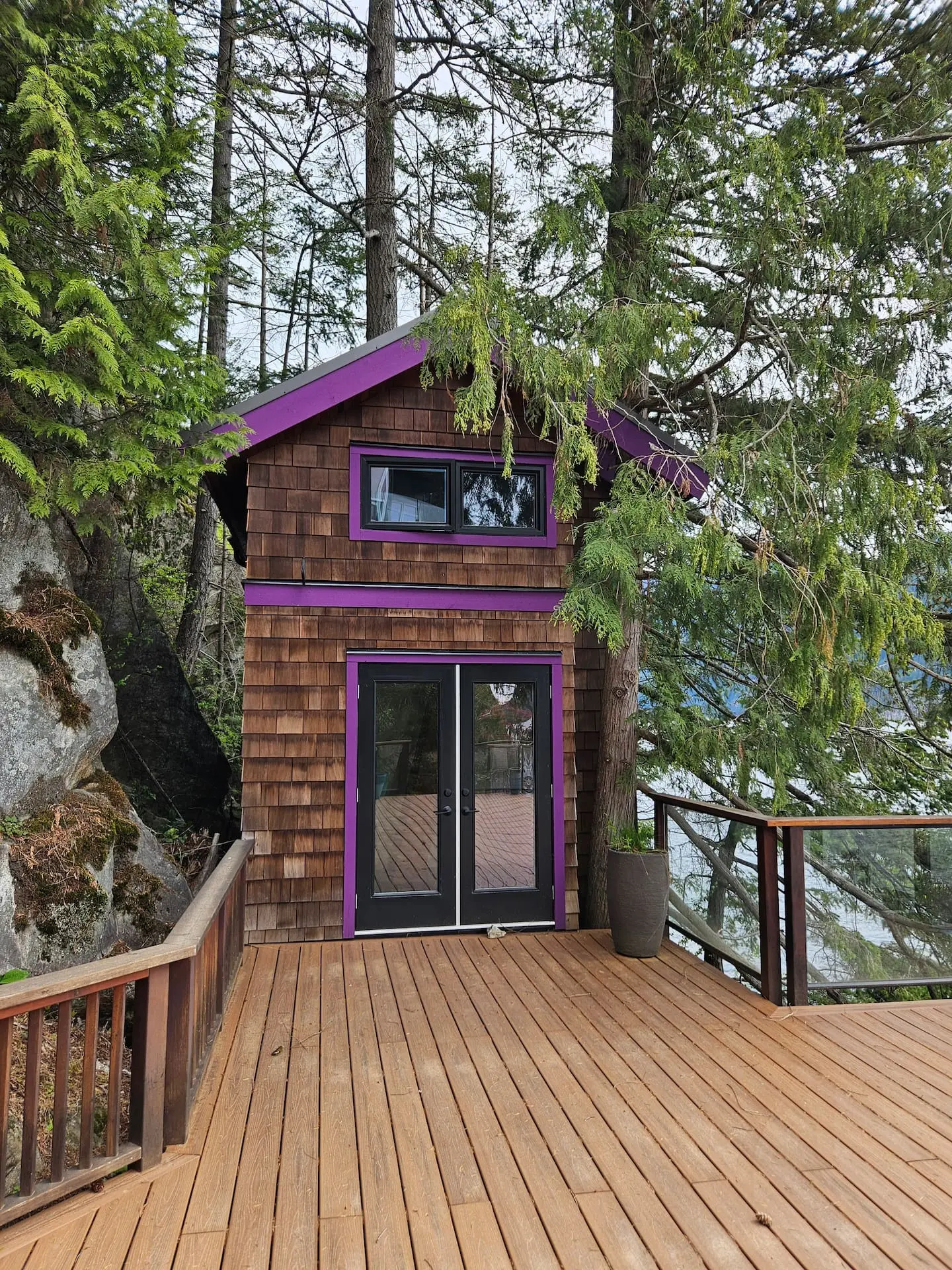 Cedar cabin with purple trim beside the deck